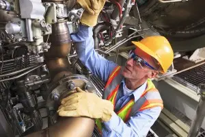 gas worker looking at machinery in protective gear